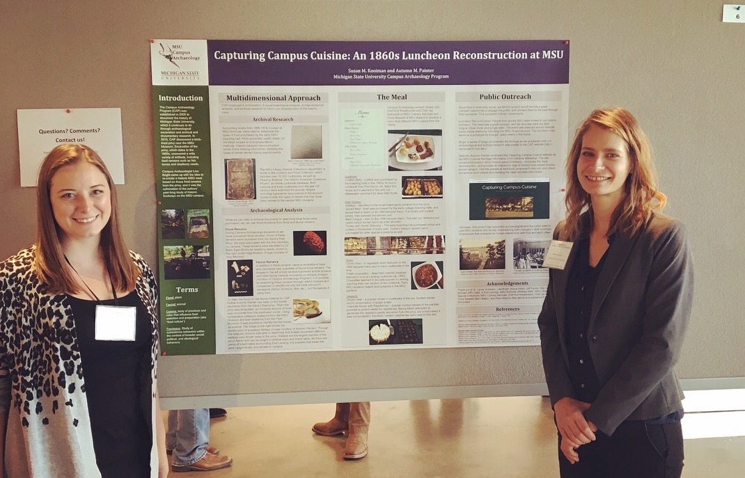 Autumn Painter and Susan Kooiman standing in front of their 2017 MAC poster - Capturing Campus Cuisine: AN 1860s Luncheon Reconstruction at MSU